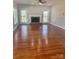 Spacious living room with hardwood floors, a brick fireplace, a ceiling fan, and windows overlooking the home's exterior at 5972 Rathlin Nw Ct, Concord, NC 28027