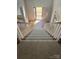 An interior staircase with white wood banisters leads to an open front door allowing natural light to flood the home's entryway at 5972 Rathlin Nw Ct, Concord, NC 28027