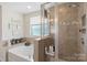 Modern bathroom featuring a walk-in shower with glass door and tiled walls, adjacent to a tub, for a spa-like experience at 6007 Cadence Ln, Indian Land, SC 29707