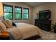 Comfortable main bedroom showing a bed with lots of pillows, a dark dresser, and three windows at 113 Angler Pl, Mooresville, NC 28117
