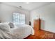 A bedroom with hardwood floors, a window with blinds, white bedding, and an oak dresser at 13922 Pilcher Dr, Charlotte, NC 28278