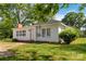 Exterior view of a white, single-story home with a well-kept lawn and mature trees at 6037 Pleasant Grove Rd, Charlotte, NC 28216