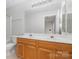 Bathroom with double sinks, wood cabinets, large mirror, and neutral colors at 7117 Flying Scotsman Dr, Charlotte, NC 28213