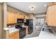 Galley kitchen with light wood cabinets, black appliances, and white countertops at 7117 Flying Scotsman Dr, Charlotte, NC 28213