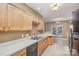 Galley kitchen with light wood cabinets, black appliances, and white countertops at 7117 Flying Scotsman Dr, Charlotte, NC 28213