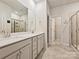 Well-lit bathroom with double sinks, vanity, and glass-enclosed shower at 7522 Porrera St, Charlotte, NC 28214
