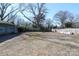 Large backyard with gravel ground cover, trees, and a wooden fence at 1024 Queens Rd, Charlotte, NC 28207