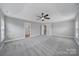 Large bedroom with tray ceiling, neutral carpet, two doors, and baseboard trim at 10319 Barrands Ln, Charlotte, NC 28278