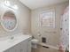 Cozy bathroom featuring a rounded mirror, vanity, window, and shower with floral curtain at 107 Cambridge Rd, Huntersville, NC 28078