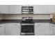 Close-up view of stainless steel oven and microwave, complemented by white cabinetry and granite countertops at 18211 Ebenezer Dr, Cornelius, NC 28031