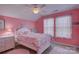 Pink bedroom featuring a decorative ceiling fan and a window dressed in light curtains at 2001 Yellow Daisy Dr, Matthews, NC 28104