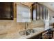 Close up shot of a kitchen sink with granite counters, tile backsplash and dark wood cabinets at 2001 Yellow Daisy Dr, Matthews, NC 28104