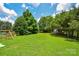 Expansive backyard with lush green grass, enclosed by trees and a wooden fence, ideal for Gathering activities at 247 Aylesbury Ln, Indian Trail, NC 28079
