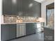 Kitchenette boasts gray cabinets, stainless steel appliances, textured backsplash, and polished concrete flooring at 2832 Arcadia Ave, Charlotte, NC 28209