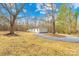 Exterior view of the home, showing a gravel driveway and wooded surround at 4105 Glenola Dr, Waxhaw, NC 28173