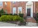 Inviting brick townhome entrance with landscaped bushes and stairs to front door at 9223 Belcaro Ln, Charlotte, NC 28273