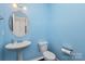 Powder room with pedestal sink, toilet, and light blue walls at 11618 Macallano Dr, Charlotte, NC 28215