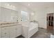 Bright and airy bathroom featuring a soaking tub, granite countertops, walk-in closet access, and white cabinets at 13020 Hindcross Dr, Huntersville, NC 28078