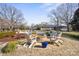 A backyard shows a stone fire pit with Adirondack chairs and a swimming pool in the background at 13031 Westmoreland Farm Rd, Davidson, NC 28036