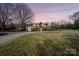 A stone and brick home has a manicured lawn and mature trees at dusk at 13031 Westmoreland Farm Rd, Davidson, NC 28036