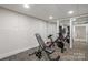 Well-lit home gym with mirrored wall, exercise bike, adjustable weight bench and storage cabinets at 13031 Westmoreland Farm Rd, Davidson, NC 28036