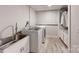 Functional laundry room with modern washer and dryer, utility sink, and storage cabinets at 13031 Westmoreland Farm Rd, Davidson, NC 28036