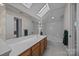 Bright bathroom with skylight, large mirror, wood cabinets, and tiled flooring at 10015 Lattice Ct, Charlotte, NC 28269