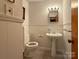 Well-lit half bath features a pedestal sink, tile flooring, and white wainscoting at 202 Cedar St, Belmont, NC 28012