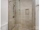 Neutral tiled shower with a glass door featuring built-in shelving and a hand held sprayer at 209 Choate Ave, Fort Mill, SC 29708