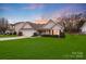 Charming one-story home with well-manicured lawn, attached garage, and inviting front porch at sunset at 2213 Genesis Dr, Monroe, NC 28110