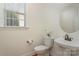 Elegant powder room with a pedestal sink, hardwood floors and lots of natural light from the window at 3013 Misty Moss Ct, Waxhaw, NC 28173