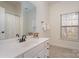 Well-lit bathroom with a large mirror, white vanity and sink, and neutral-toned tile flooring at 3013 Misty Moss Ct, Waxhaw, NC 28173