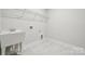 Convenient laundry room with sink, shelving and marble floor at 3209 Whispering Creek Dr, Indian Trail, NC 28079