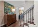 Inviting entryway with hardwood floors, staircase, and a decorative chest with colorful artwork at 4334 Silo Ln, Charlotte, NC 28226