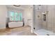 Bright bathroom featuring a soaking tub, walk-in shower with glass door, and wood look tile flooring at 4607 Ferguson Cir, Waxhaw, NC 28173