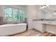 Bright bathroom featuring a soaking tub, vanity, and wood look tile flooring at 4607 Ferguson Cir, Waxhaw, NC 28173