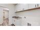Convenient laundry room featuring a sink with marbled countertops and white cabinets above at 4607 Ferguson Cir, Waxhaw, NC 28173