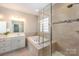 Bathroom featuring glass enclosed shower, tub, double sink with quartz countertop, and glass block window at 5115 Waterloo Dr, Fort Mill, SC 29708