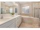 Tiled bathroom featuring double sinks, quartz countertops, tub, and glass shower door at 5115 Waterloo Dr, Fort Mill, SC 29708