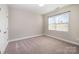 Empty bedroom featuring neutral walls, carpet, a window, and a door at 5115 Waterloo Dr, Fort Mill, SC 29708