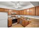 Kitchen features wood cabinets, laminate countertops, and white appliances, complemented by a bright ceiling fan at 5818 Harris Grove Ln, Charlotte, NC 28212