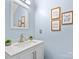 Bright bathroom with a single sink vanity, a large mirror, and decorative wall art at 1107 Stonehenge Ln, Charlotte, NC 28216