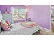 Charming bedroom with lilac-colored walls, a sunny window, and a playful rainbow-themed blanket at 1107 Stonehenge Ln, Charlotte, NC 28216