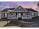 Gray house with white trim, front porch, and mature trees in the yard at 114 Juanita Dr, Pineville, NC 28134