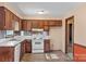 Cozy kitchen with wood cabinets, white appliances, and orange accent wall at 214 Costner Dr, Bessemer City, NC 28016