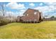 View of a two-story brick home, complemented by a lush green lawn and mature trees in the backyard at 2865 Scarborough Ct, Gastonia, NC 28054