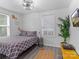 Well-lit bedroom with gray patterned bedding, a plant, and a view through the window at 3021 Botany St, Charlotte, NC 28216