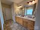 Bright bathroom featuring double sinks, a large mirror, vanity lighting, and a window at 5421 Roberta Meadows Ct, Concord, NC 28027