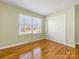 Simple bedroom with hardwood floors and a large window at 6412 Wheeler Dr, Charlotte, NC 28211