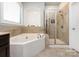 Bright bathroom showcasing a garden tub, a glass shower with tiled surround, and a large window at 8177 Breton Way, Harrisburg, NC 28075